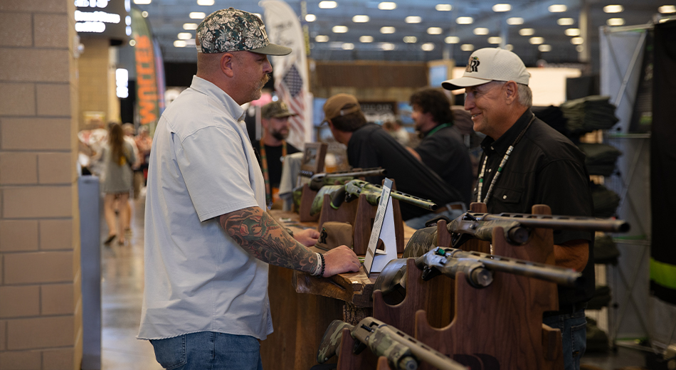 Expo vendor and customer looking at shotguns